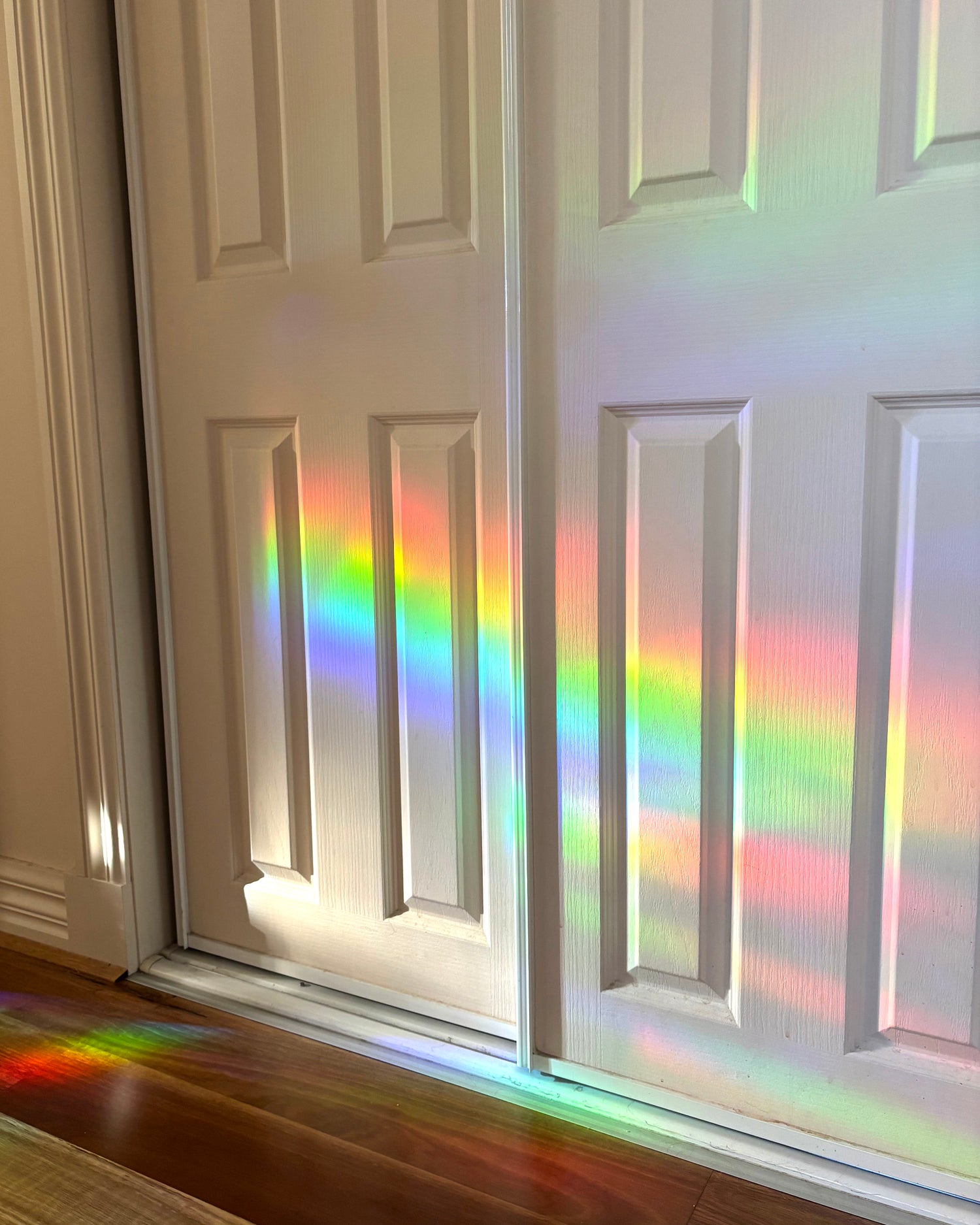 White door with rainbow reflections on a wooden floor