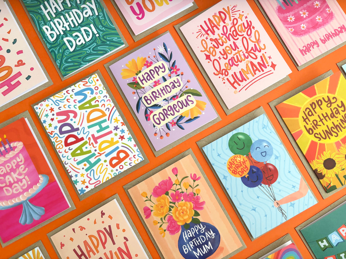 A grid arrangement of colourful birthday greeting cards with various playful designs and text, displayed against a bright orange background.