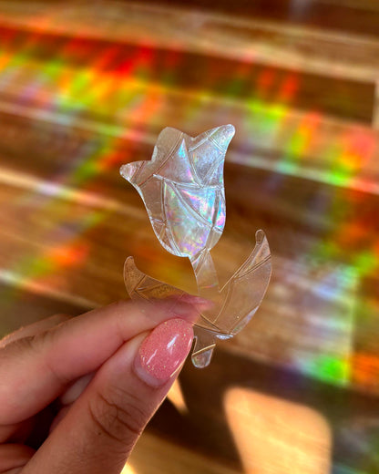 Iridescent tulip-shaped sun catcher sticker held by a hand with a colourful, blurred background