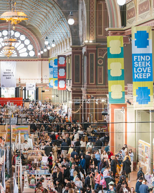 Large indoor marketplace with people shopping, colorful signs, and a high ceiling.